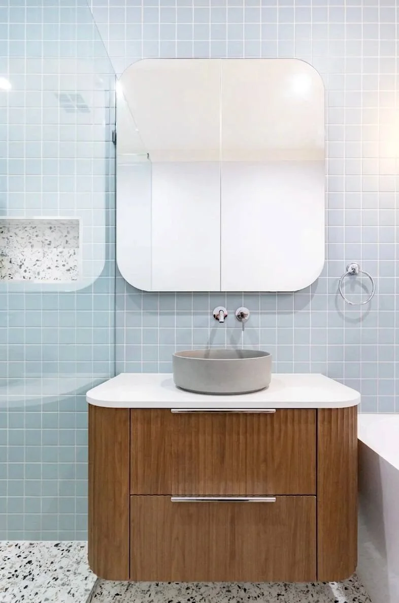 Close-up of walnut vanity with concrete basin, chrome wall-mounted faucet, and blue subway tile backdrop — Redmond WA