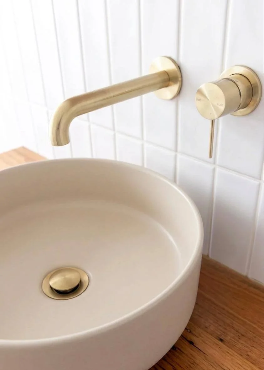 Close-up of recycled timber vanity with round ceramic basin and brushed brass wall-mounted fixtures — bathroom renovation Bellevue