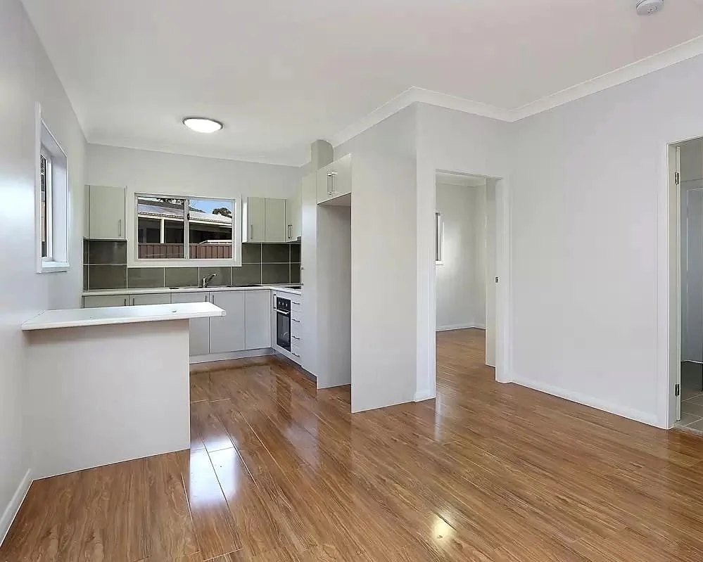 Open-plan kitchen living area detached ADU Renton — gray cabinets peninsula bar LVP flooring two bedrooms