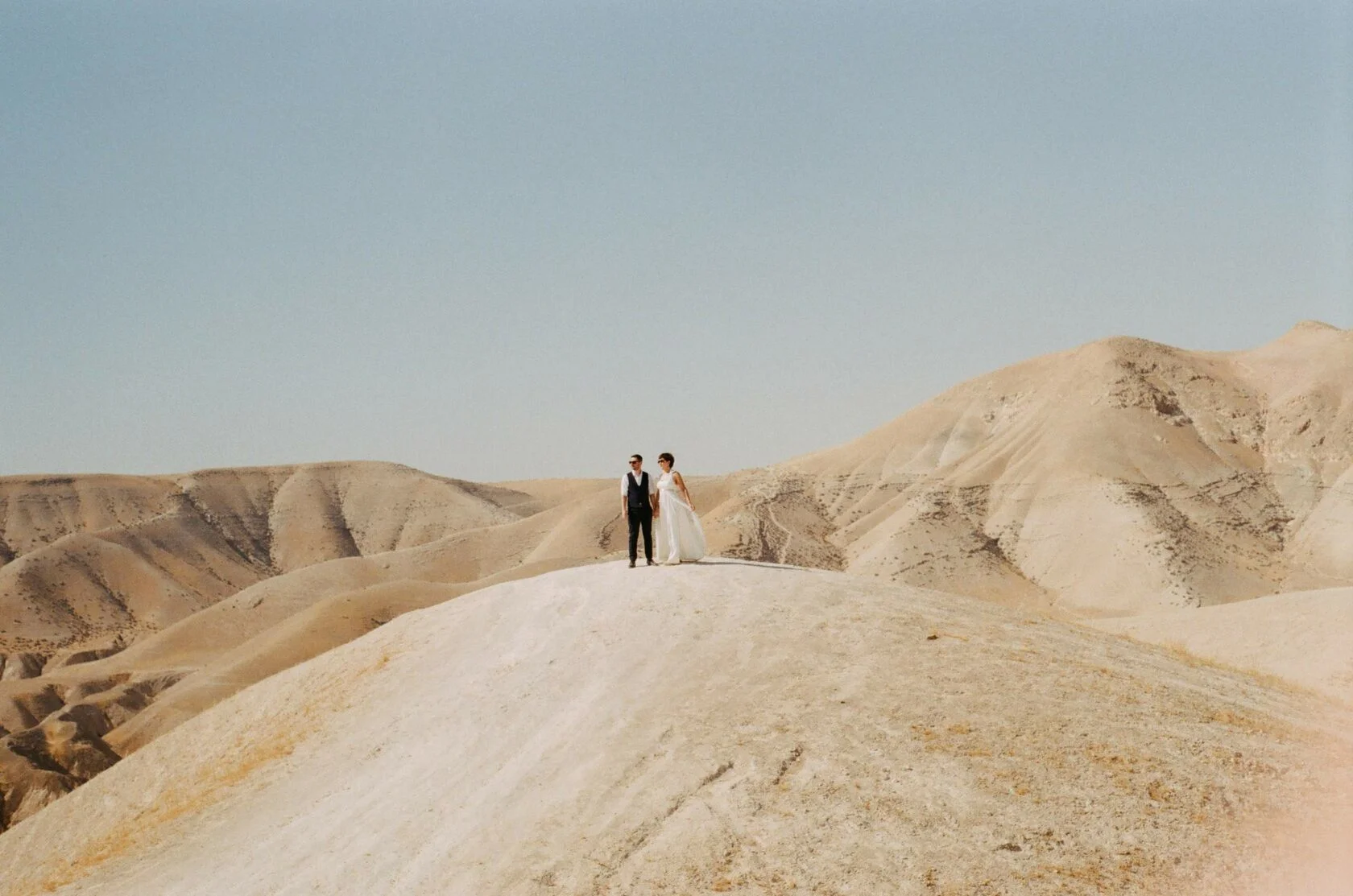 Bride and groom standing on a white hill in the Judean desert