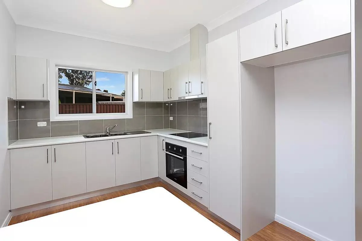 Kitchen detail backyard cottage Renton — gray cabinets white quartz tile backsplash built-in oven pantry