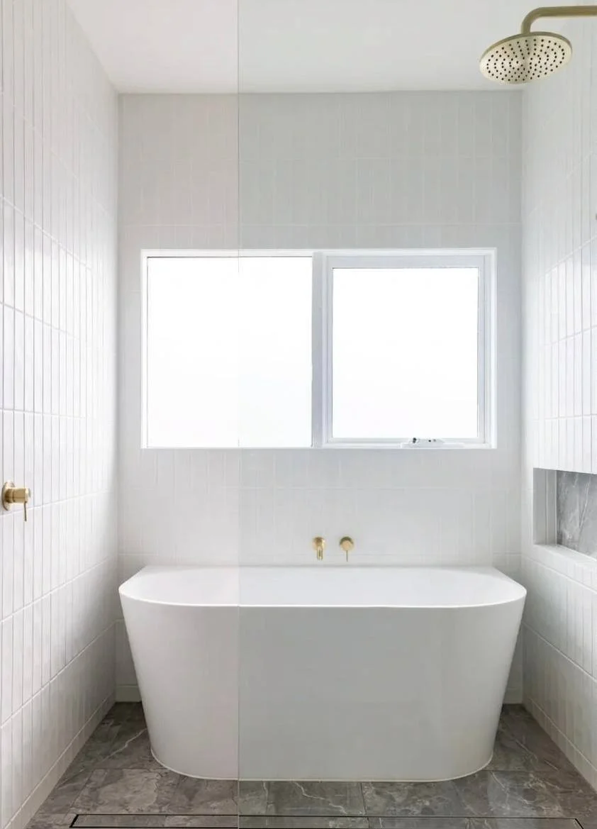 Freestanding white tub with brushed brass faucet, rain showerhead, and built-in marble niche — Bellevue WA bathroom