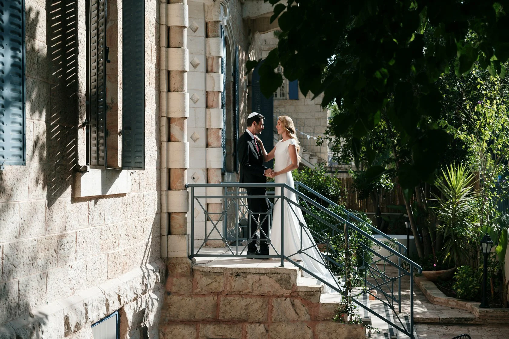 Bride and groom on the stairs of an old Jerusalem stone house