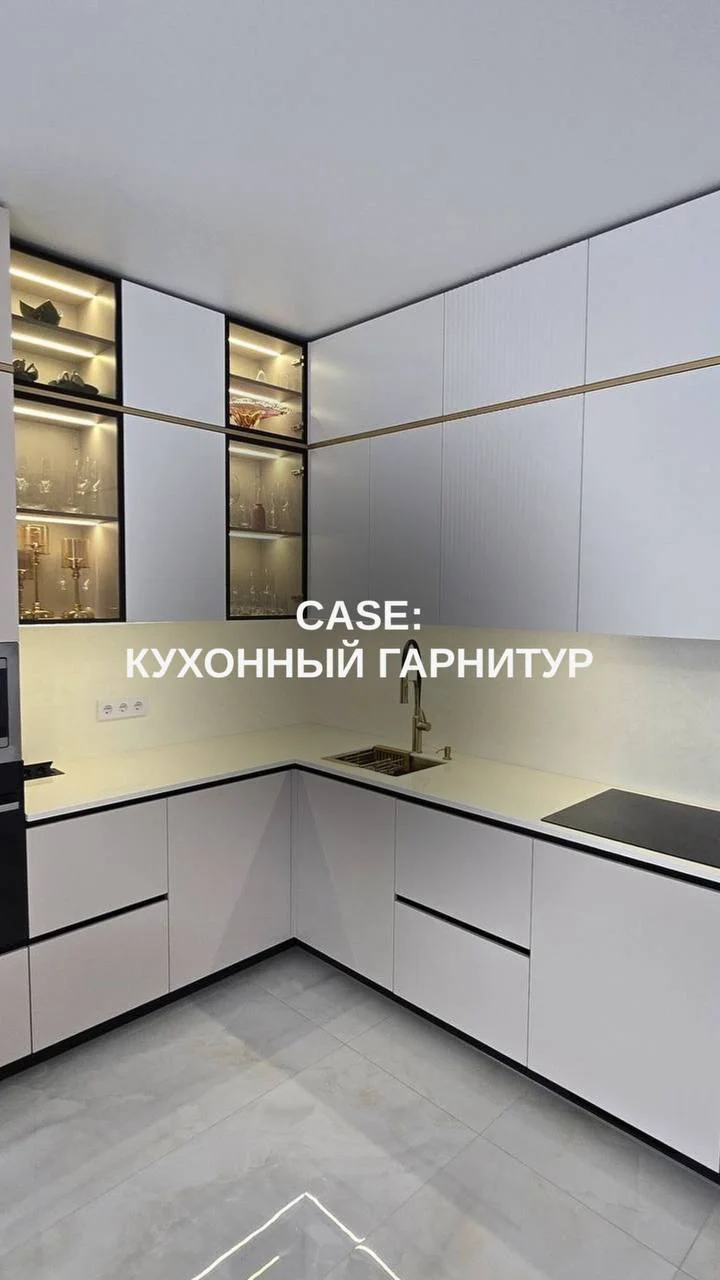Общий вид минималистичной угловой кухни со светлыми фасадами и вертикальными витринами