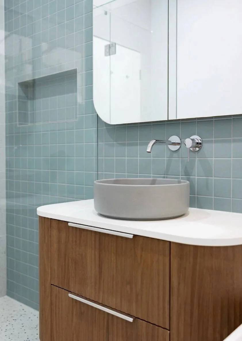 Frameless glass shower with terrazzo walls, walnut vanity, and concrete basin — bathroom renovation Redmond WA