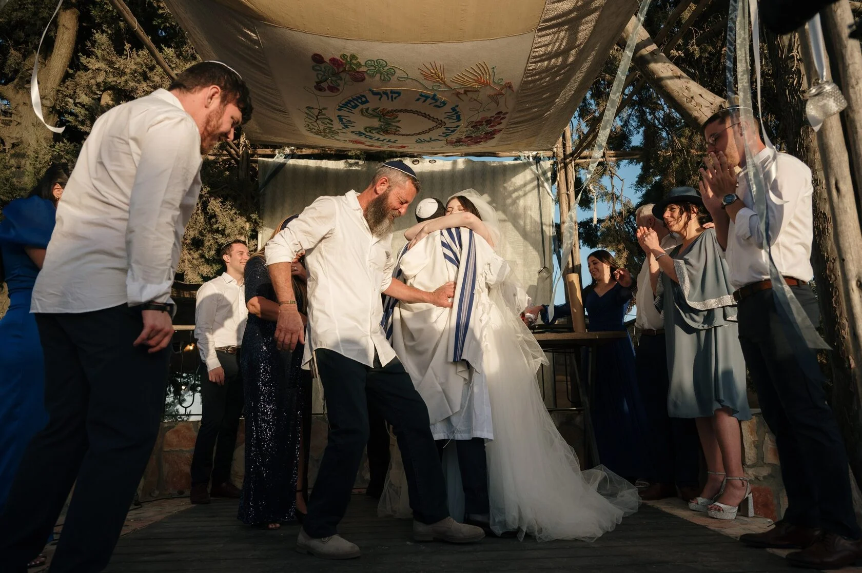 Guests embrace the couple under the chuppah