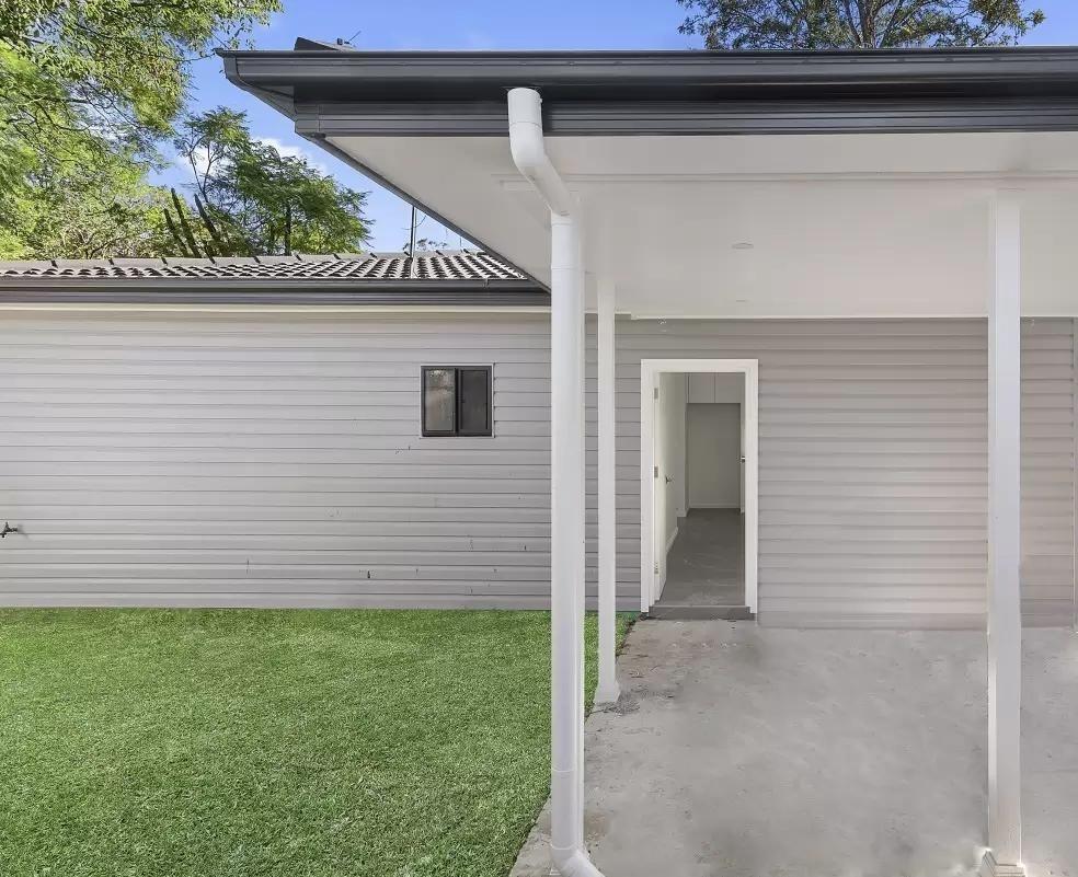 Modern DADU side entry view Edmonds — covered porch white siding dark roof gutters