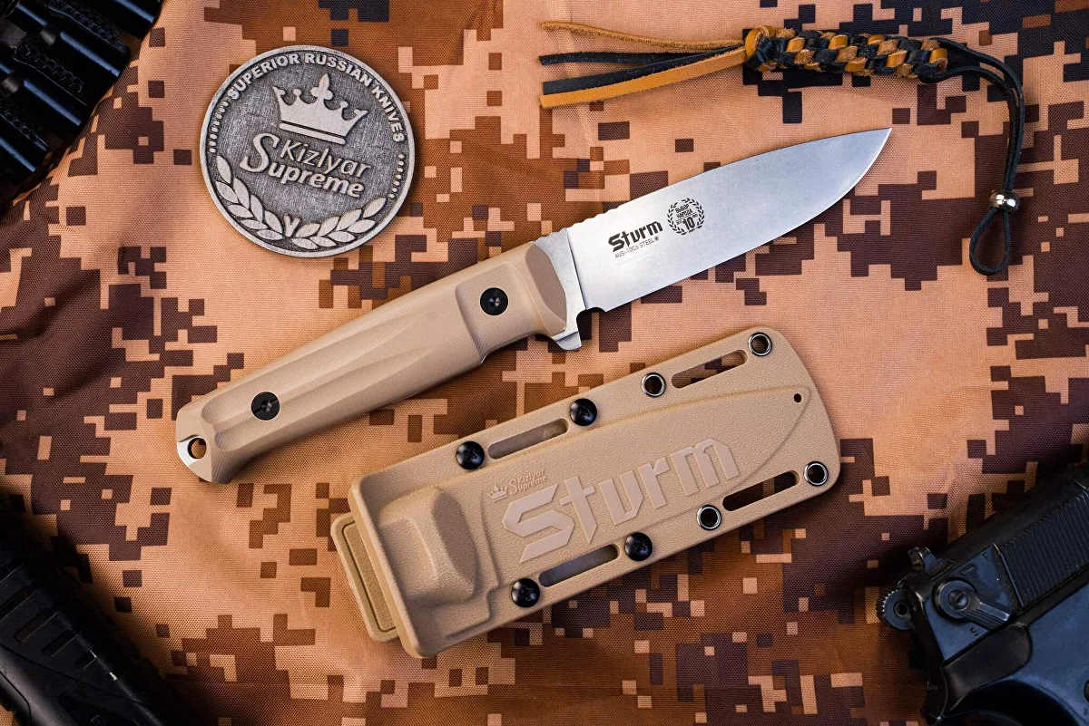 Tan Kizlyar Supreme Sturm fixed-blade knife and matching sheath on camouflage fabric