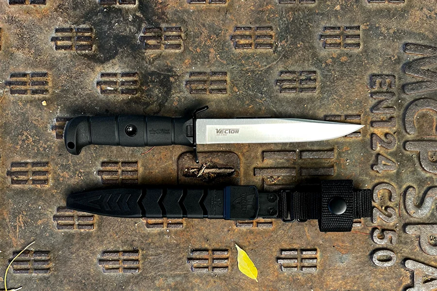 Black Vector knife and sheath shown together on an industrial surface