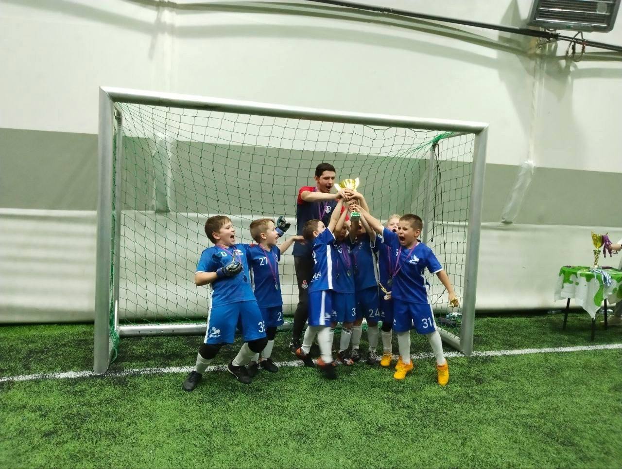 Команда детей поднимает кубок после финального турнира летней смены Торнадо