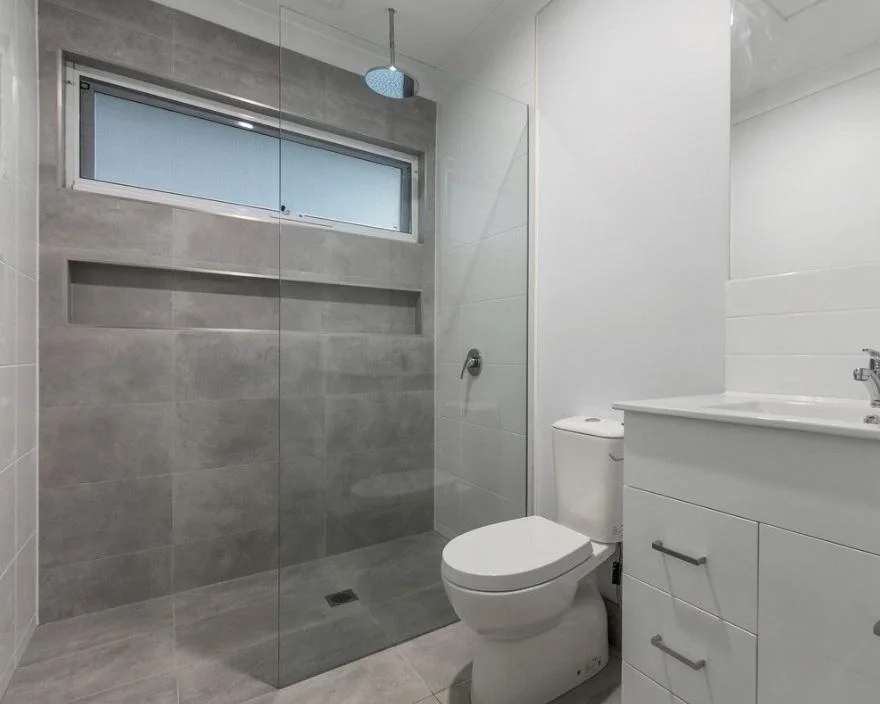 DADU bathroom Bothell — grey porcelain tile frameless shower ceiling rain head niche shelf