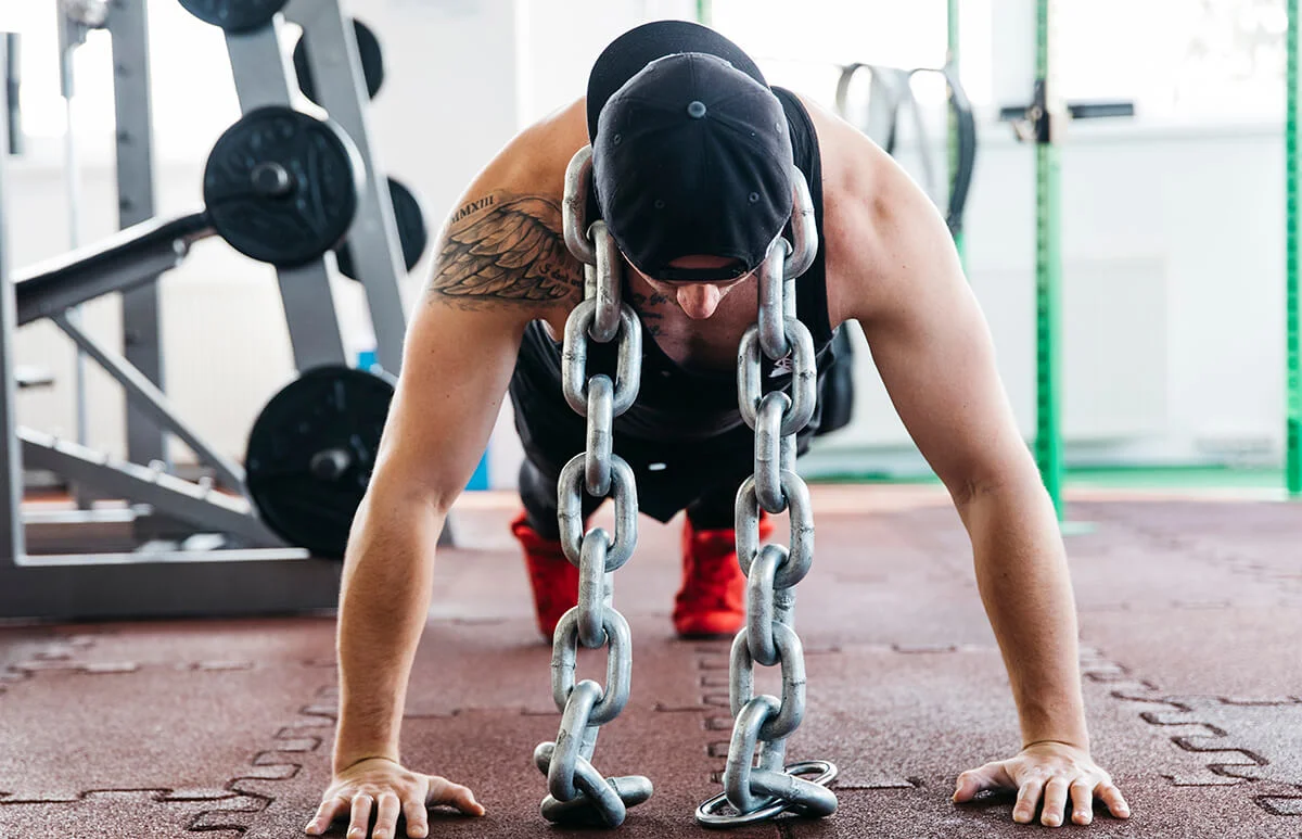 Athlete performing a chain-loaded push-up in a gym