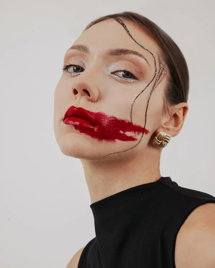 Beauty editorial portrait with a bold red lip and graphic hair detail