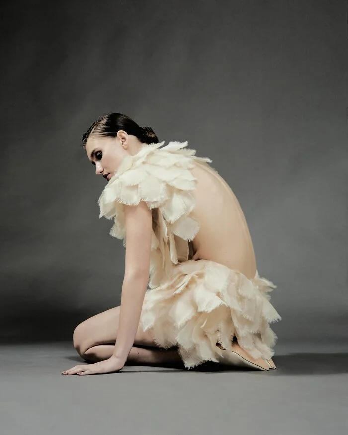 Fashion editorial model in a sculptural cream feather dress