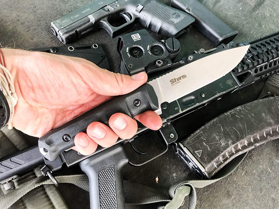 Black-handled Sturm knife held over tactical equipment
