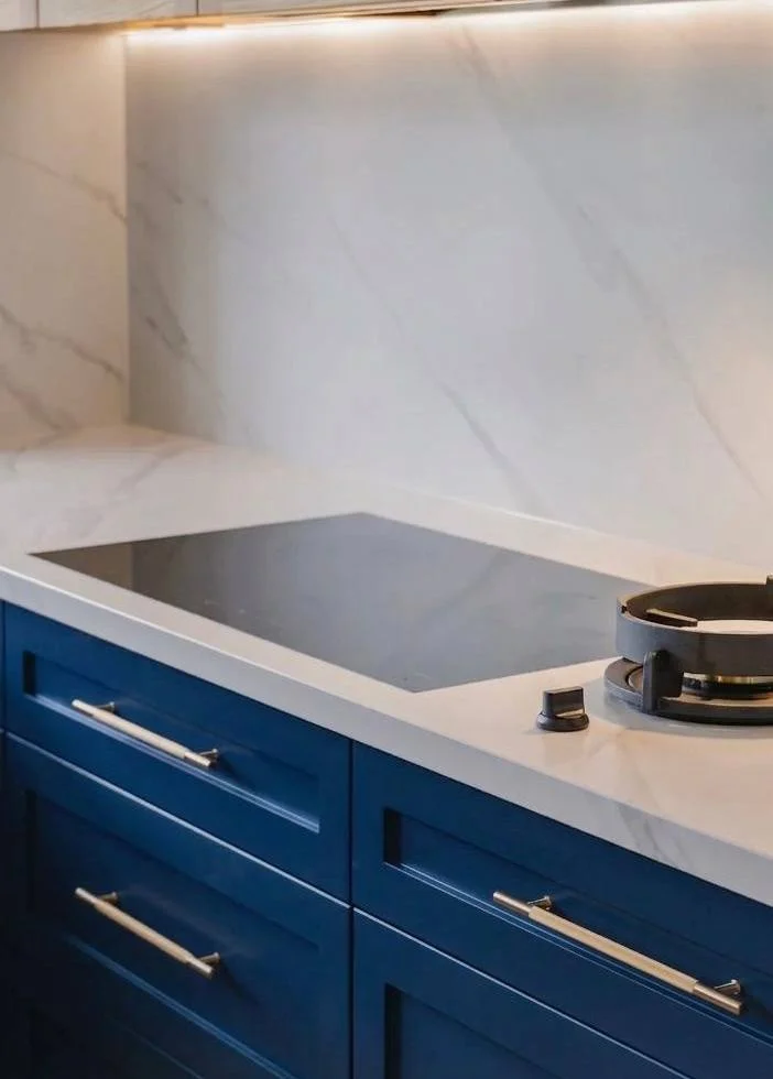 Brushed brass gooseneck faucet, glass dome pendant, marble island countertop, navy cabinets — kitchen renovation Woodinville WA