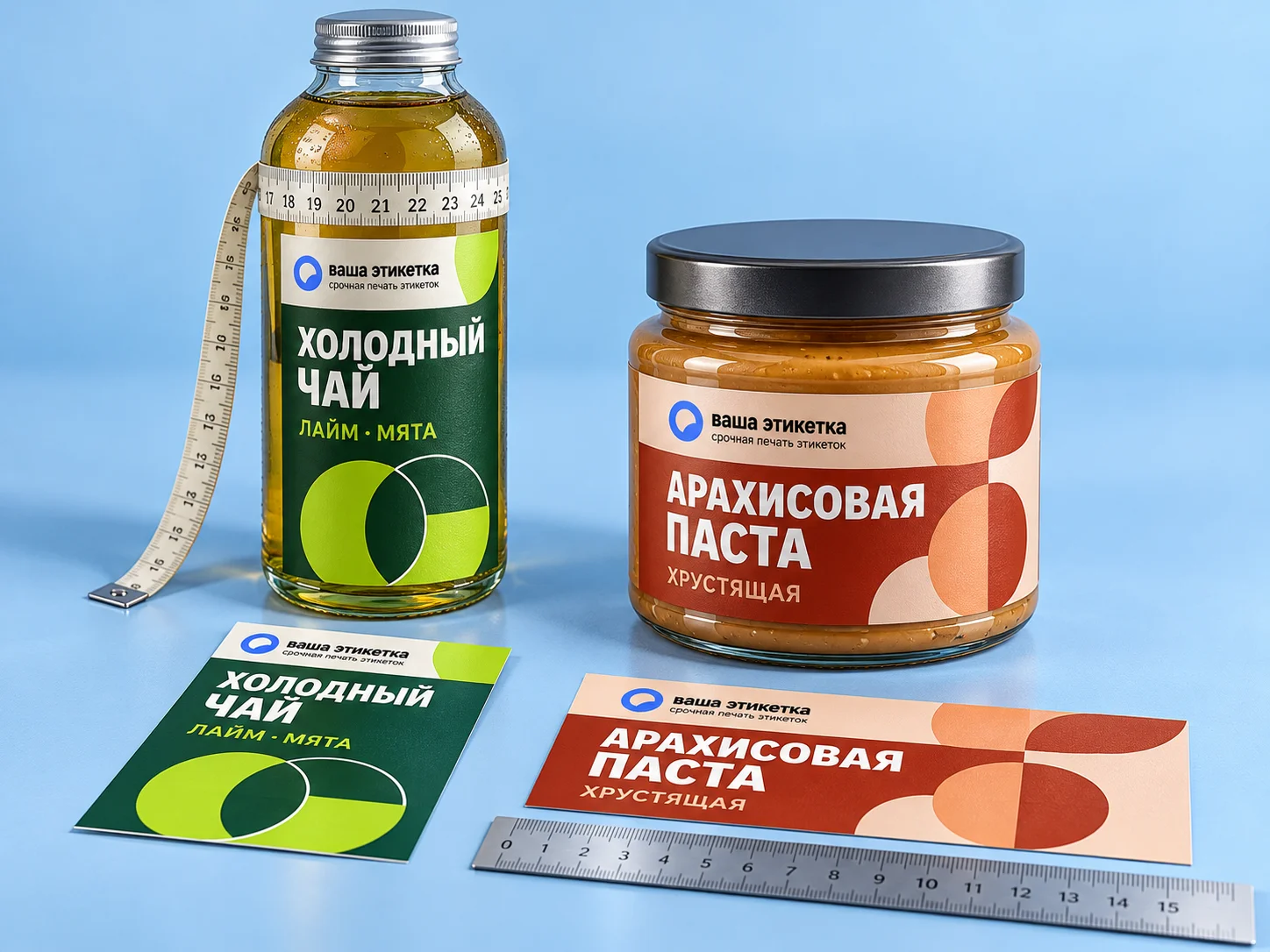 Бутылка холодного чая с измерительной лентой, банка арахисовой пасты и образцы наклеек с линейкой: замеры для расчёта размера наклейки