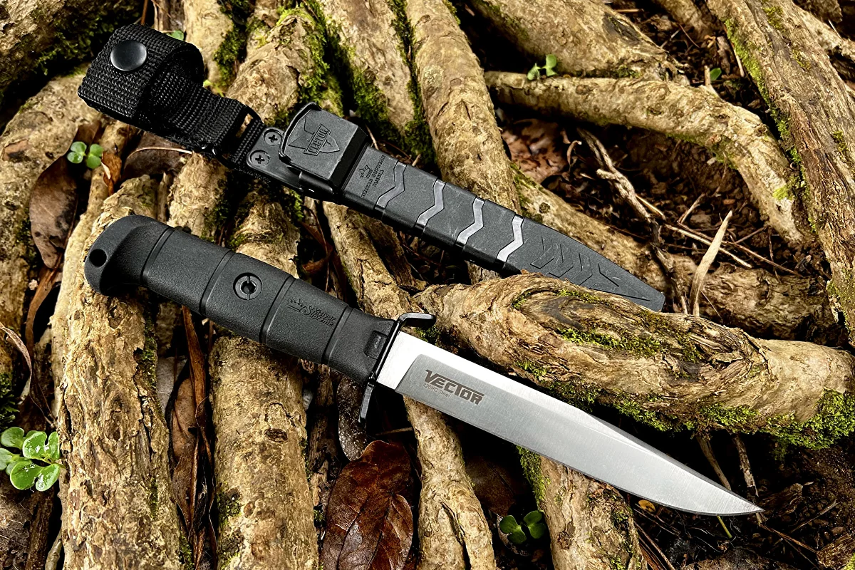 Kizlyar Supreme Vector knife beside its slim tactical sheath on woodland roots