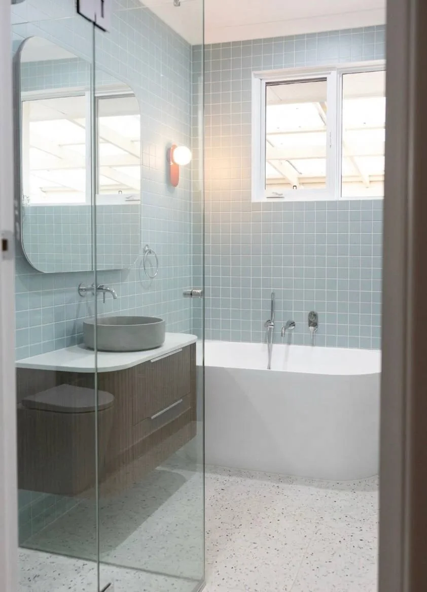 Floating walnut vanity with concrete vessel basin, chrome faucet, and rounded mirror cabinet on blue tile — Redmond WA