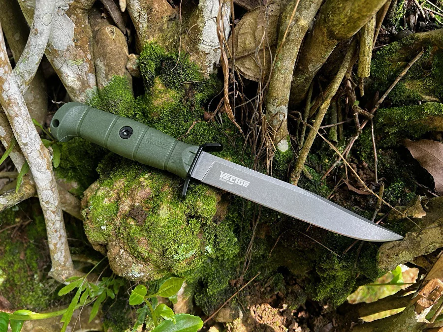 Olive Vector knife placed across moss and woodland roots