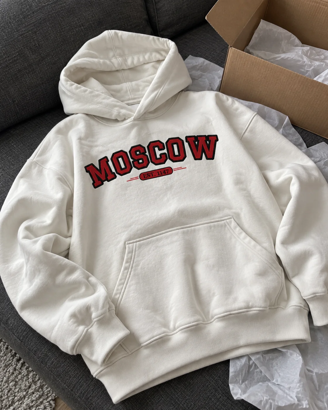 Белое худи с вышивкой MOSCOW рядом с открытой коробкой