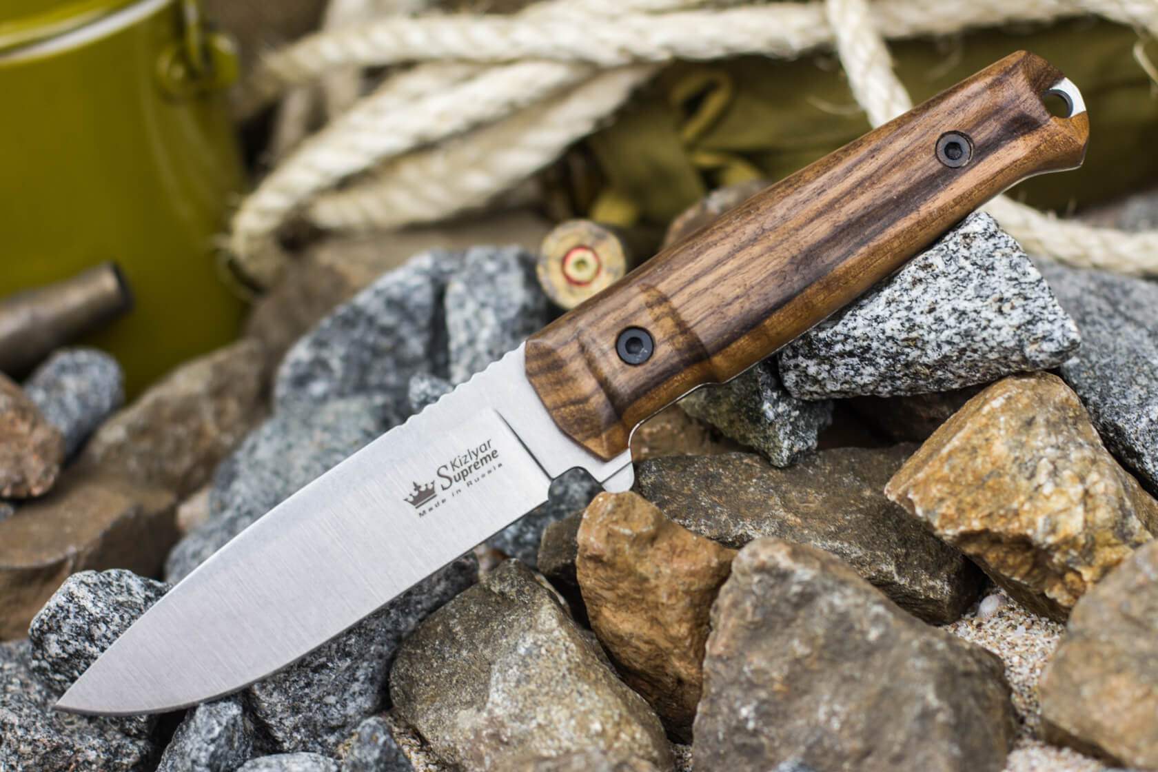 Walnut-handled Sturm fixed-blade knife on stone and field equipment
