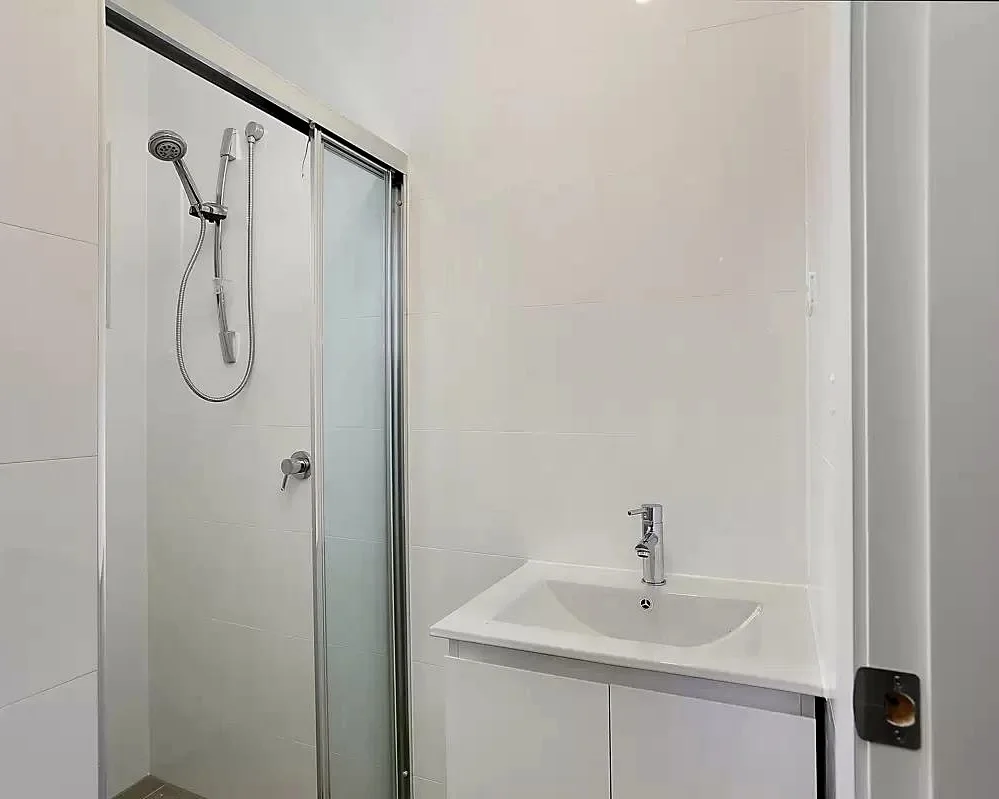 Bathroom shower backyard cottage Renton — sliding glass door white tile vanity chrome fixtures