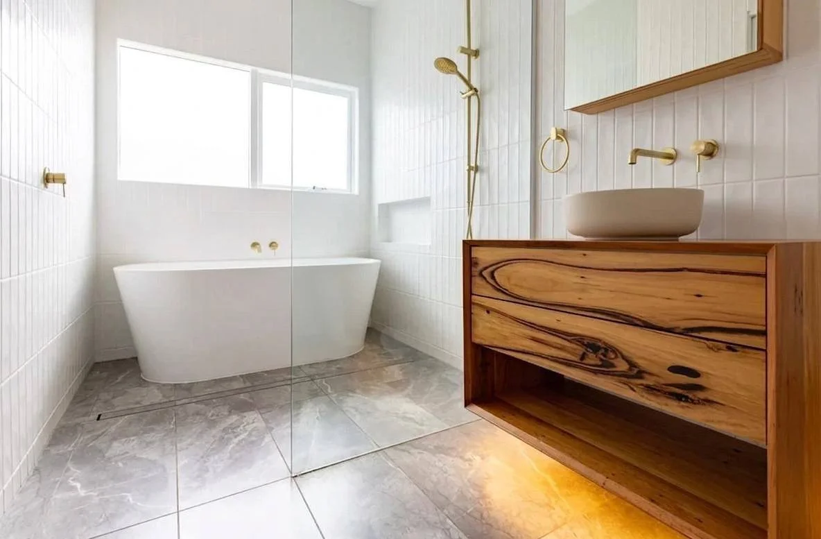 Bathroom after renovation — recycled timber vanity, brushed brass, frameless glass, Bellevue WA